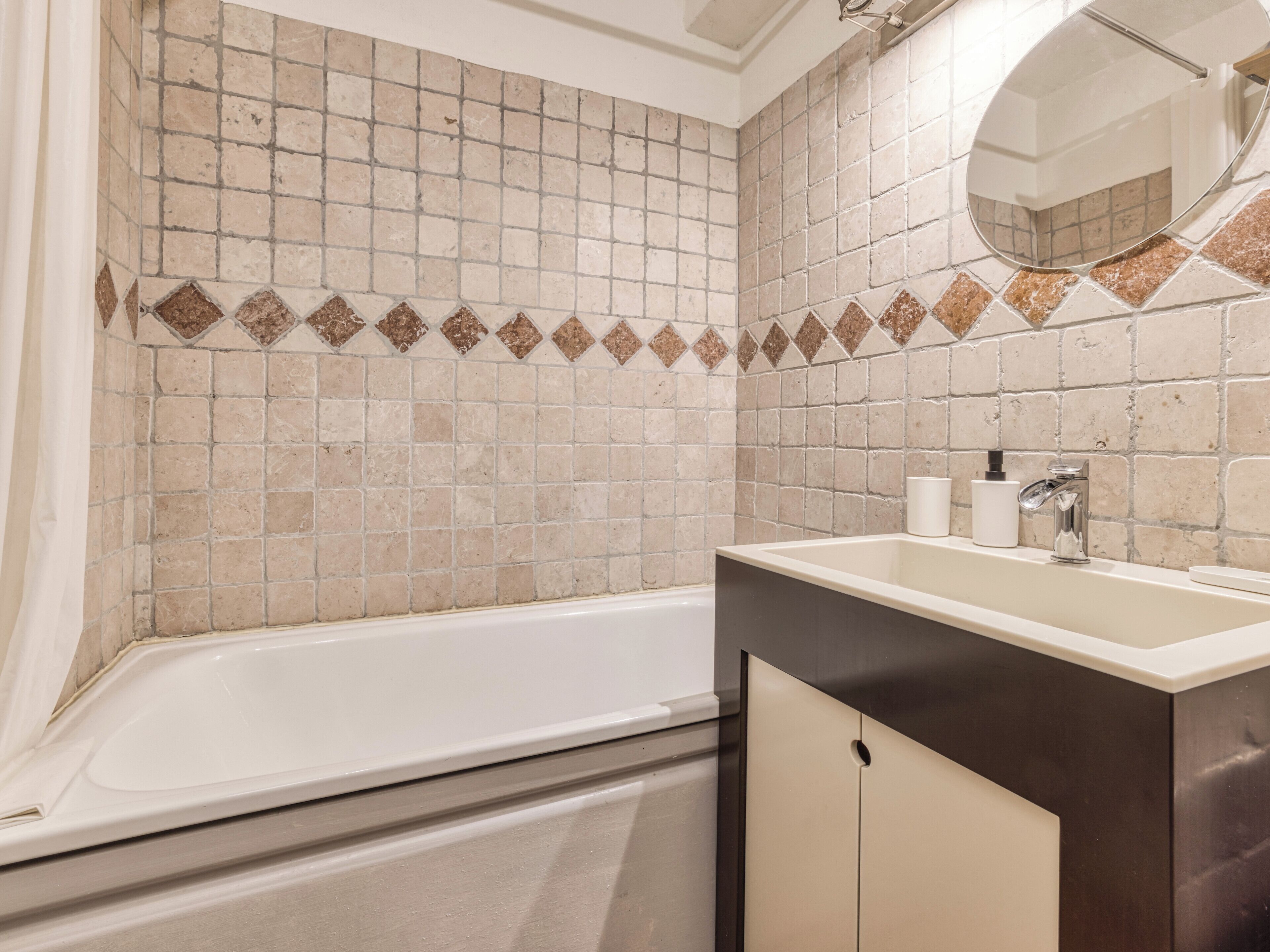 A bathroom with a bathtub, a sink, and a mirror.