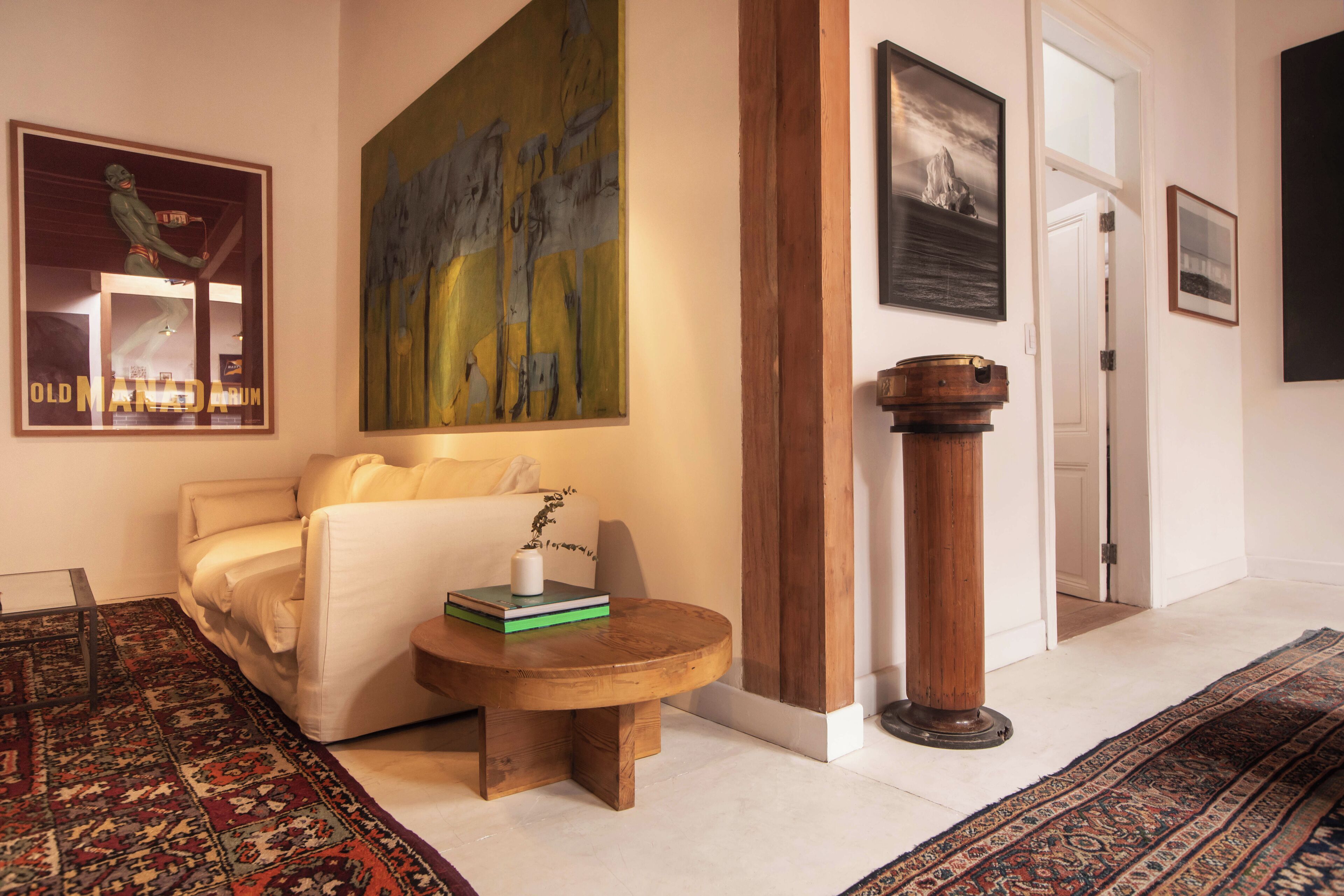 A living room with a sofa, a coffee table, a painting, and a wooden column.