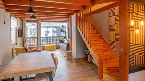 Un intérieur en bois comprenant un coin repas, un canapé et un escalier.