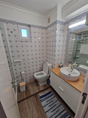 Een badkamer met toilet, wastafel en spiegel.