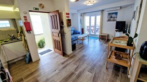 A spacious living area with a wooden floor, a ceiling fan, a sofa, a coffee table, and a TV. - Amazing Terrace Costa da Caparica (Costa da Caparica)