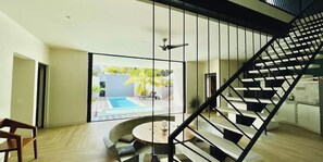 Een modern interieur met een trap, een zwembad en uitzicht op de omgeving.