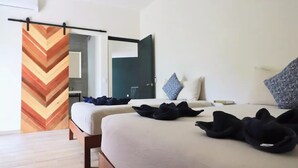 A hotel room with a bed, a chest of drawers, a mirror, and a door with a chevron-patterned curtain. - Casa Búho I Unique & Spacious 4Br Villa 10 people (Tulum)