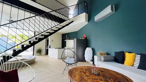 A modern living room with a staircase, a dining area, and a sofa with cushions. - Casa Búho I Unique & Spacious 4Br Villa 10 people (Tulum)