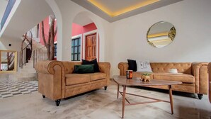 A spacious living area with two sofas, a coffee table, and a staircase leading to an upper floor.