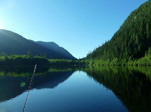 A calm lake surrounded by forested hills.