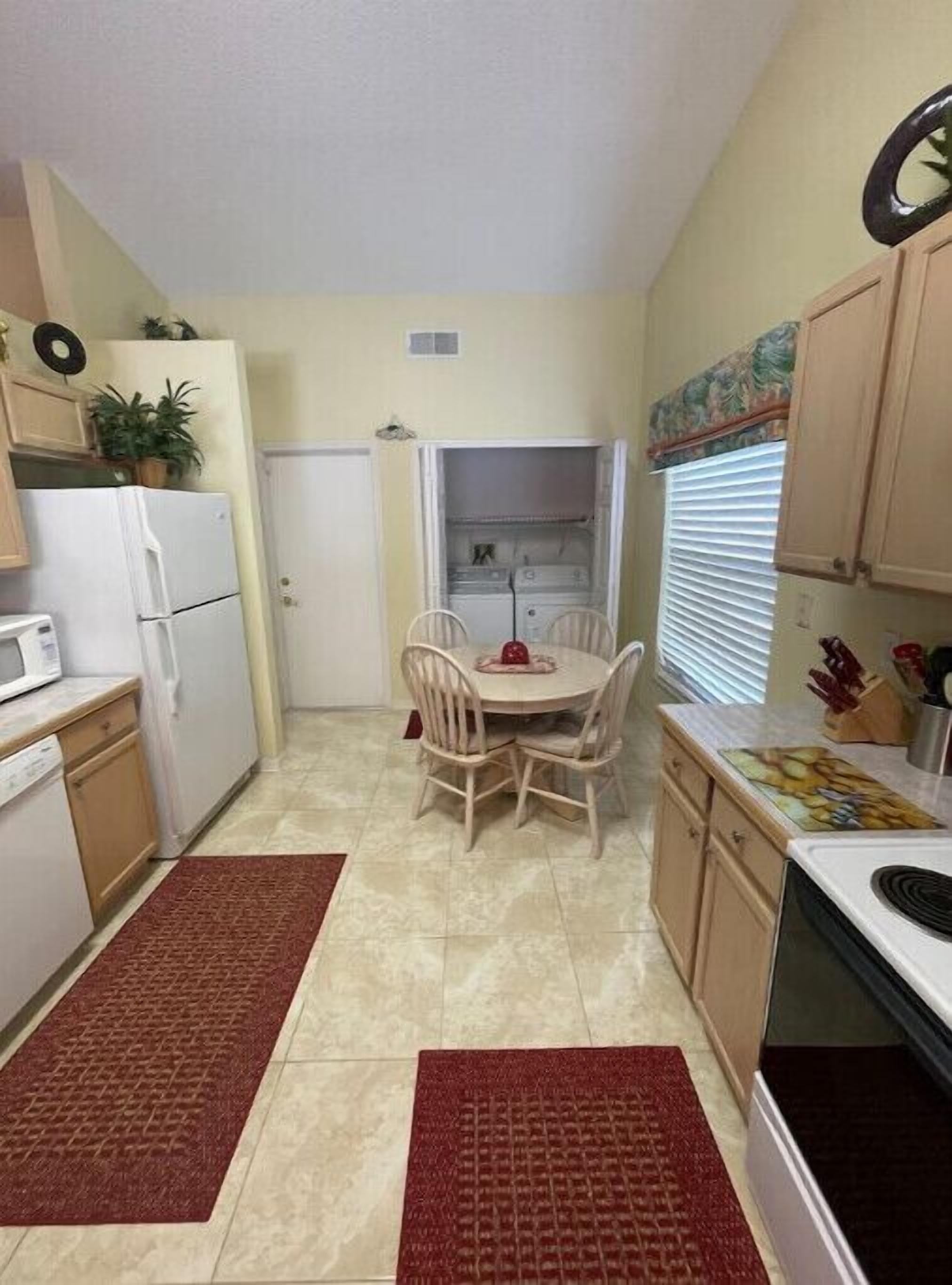 A compact kitchen with a dining table, chairs, a refrigerator, a microwave, and a stove.