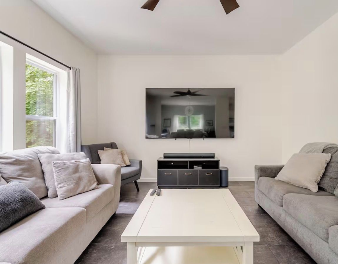 A modern living room with two sofas, a flat-screen TV, and a coffee table.