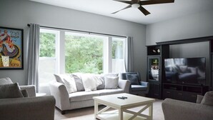 A living room with a sofa, armchairs, a coffee table, a TV, and a ceiling fan.
