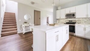 A modern kitchen with white cabinetry, a central island, and a microwave.