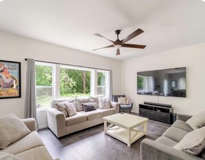 A living room with a sofa, a coffee table, a TV, and a ceiling fan.