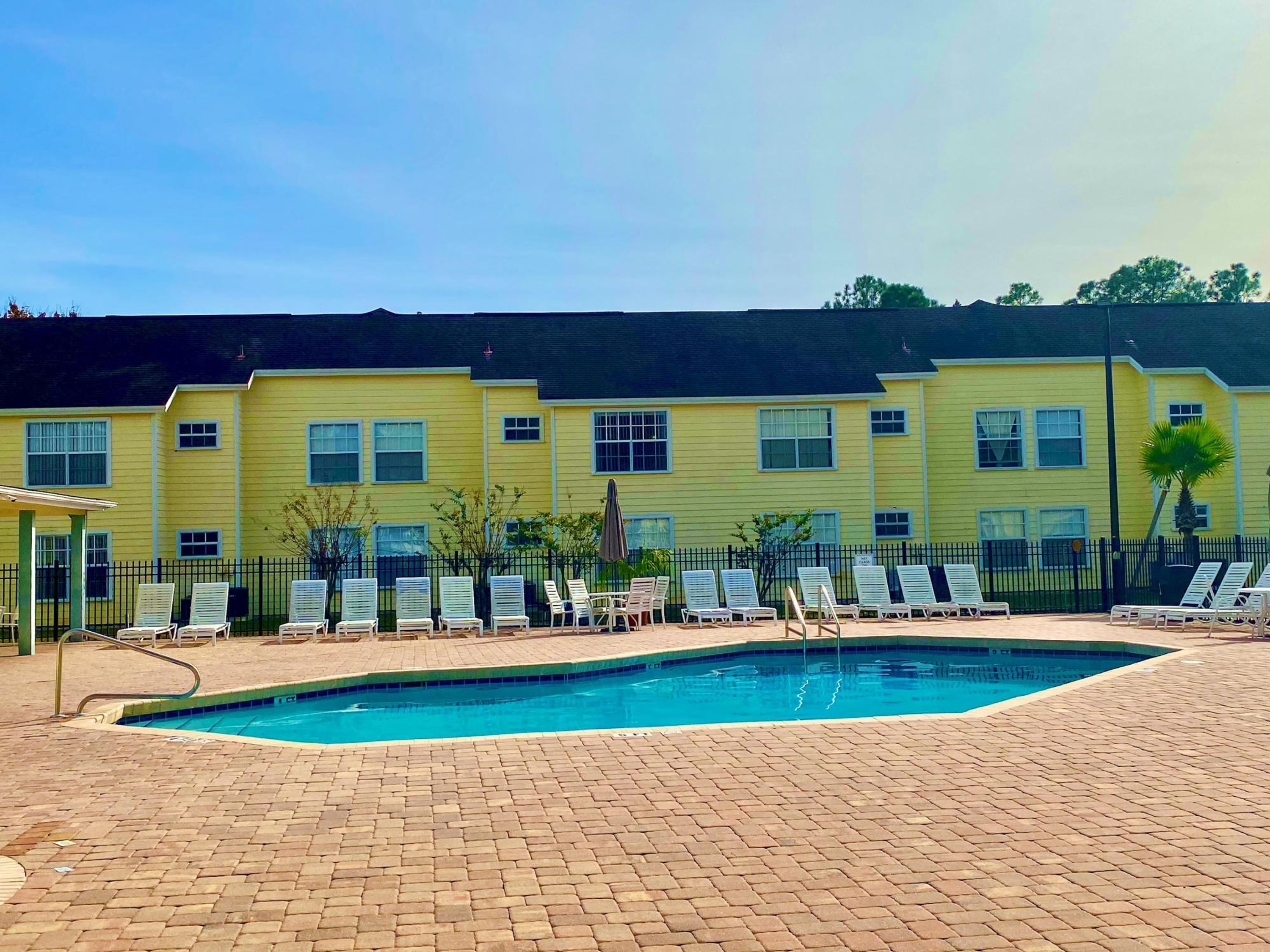 A pool area with lounge chairs and a brick patio.