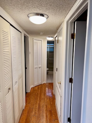 A hallway with wooden flooring, white doors with louvered tops, and a ceiling light fixture. - Grand Family Deluxe 3BD Condo Near Disney Universal 22 (Kissimmee)