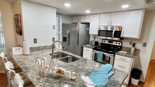 A modern kitchen with granite countertops, stainless steel appliances, and white cabinetry. - Grand Family Deluxe 3BD Condo Near Disney Universal 22 (Kissimmee)