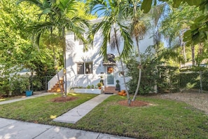 A white house with a front porch, palm trees, and a well-maintained lawn. - Families Welcome 3 Bedroom Oasis w/Parking (Miami)