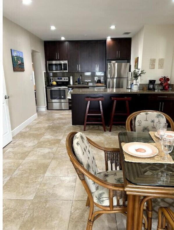 A modern kitchen with dark cabinets, stainless steel appliances, and a central island with stools.