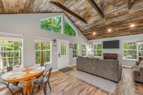 Relax in this spacious living area with a high ceiling, featuring a large dining table and comfortable seating.