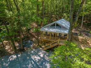 Escape to a secluded cabin surrounded by dense forest, featuring a deck with outdoor seating.