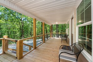 Relax in this serene outdoor space with a deck, chairs, and table, surrounded by lush greenery.