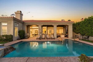 A modern house with a swimming pool, outdoor seating, and a patio area.