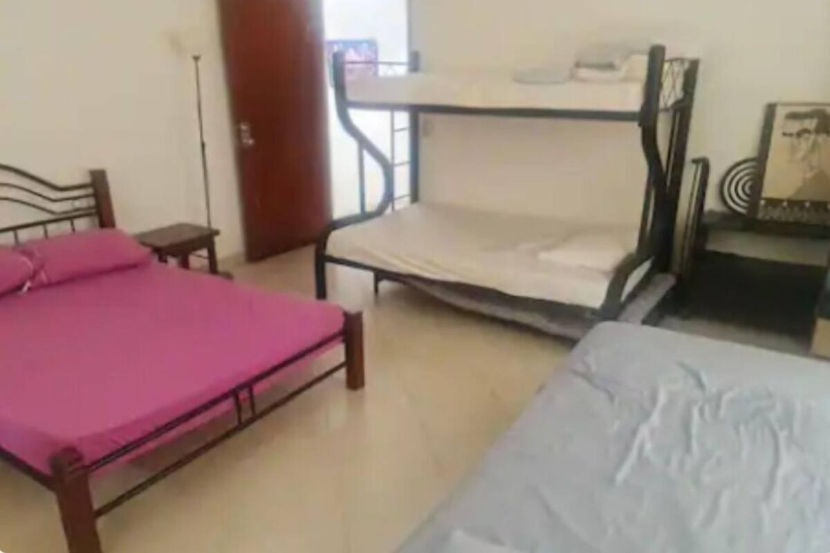 A room with a bunk bed, a single bed, a small table, and a chair.