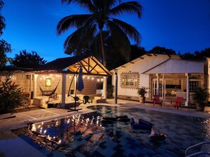 A pool area with a hammock, lounge chairs, and a covered seating area with string lights. - Finca Los Monitos (Ricaurte)