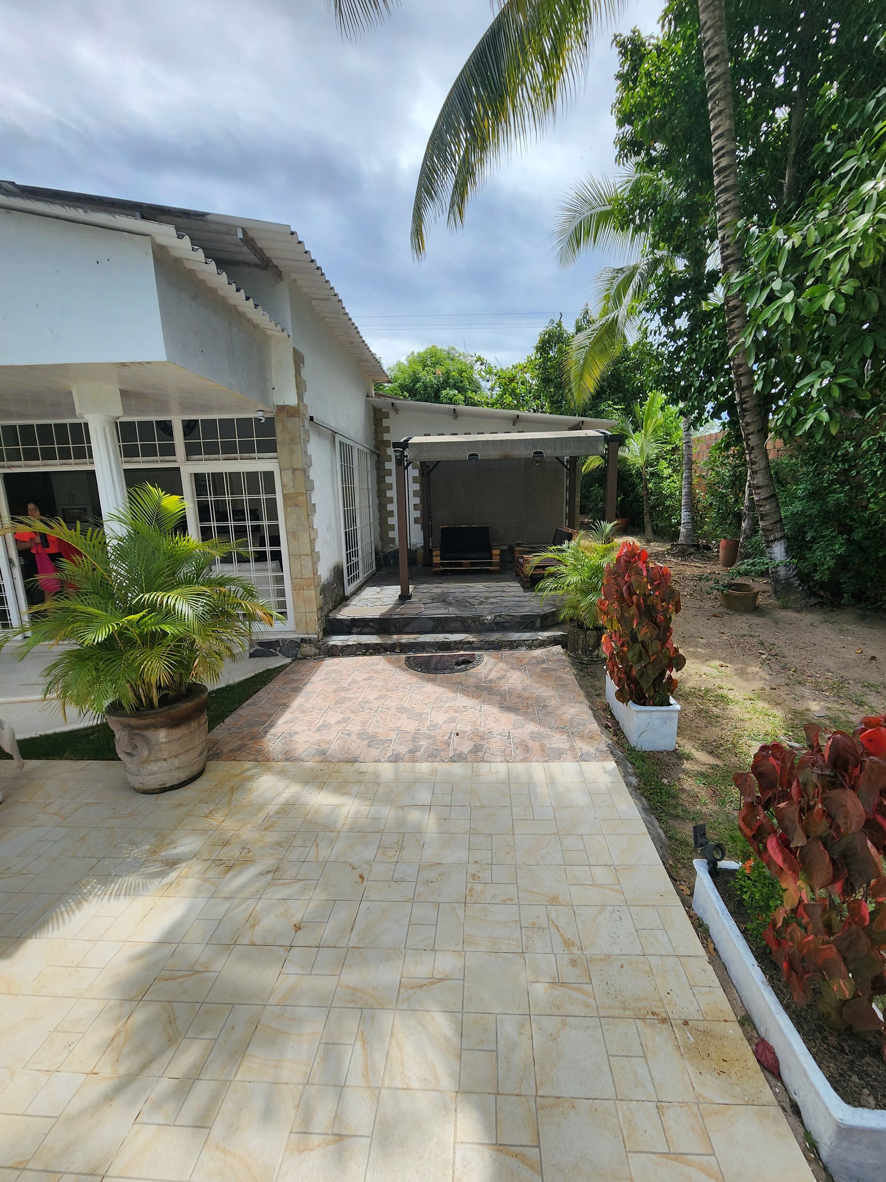 A covered outdoor seating area with a tiled patio leading to a building entrance.