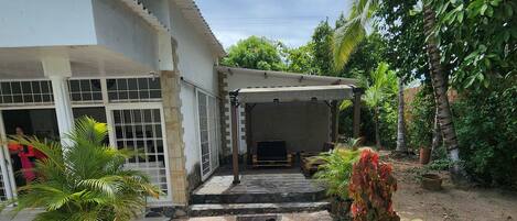 A covered outdoor seating area with a tiled patio leading to a building entrance.