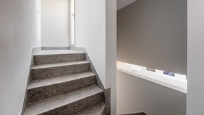 Una escalera de diseño moderno que conduce a una plataforma con un estante blanco que exhibe objetos pequeños.