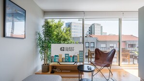 Un salón moderno con un sofá, un sillón, una mesita y un ventanal con vistas a la ciudad.