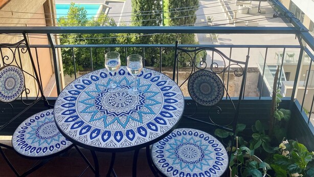 A balcony with a table and chairs, overlooking a courtyard with trees and buildings. - Comfortable two-room apartment near Santa Maria Novella station (Firenze)