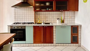 A kitchen with wooden cabinets, a gas stove, a sink, and a tiled backsplash. - Comfortable two-room apartment near Santa Maria Novella station (Firenze)