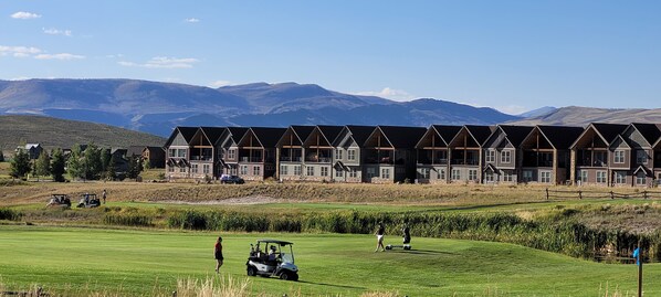 A row of log cabin-style buildings with a golf course in the foreground.