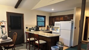 A compact kitchen with a central island, wooden cabinets, a white refrigerator, and a built-in oven. - Cozy Lakefront Home; Close to skiing and waterparks (Blakeslee)
