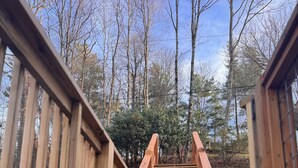 A wooden deck leading to a gate with a lattice design, surrounded by trees and a clear sky. - Windsong yurt, in the treetops, hottub on the top deck, petfriendly, stargazing (Hillsville)