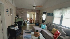 A cozy living room with a sofa, a coffee table, and a fireplace. There is a dining area with chairs and a table. - Sandy beach retreat! 500 ft to beach! 3 miles to the quaint village of Lexington (Lexington)