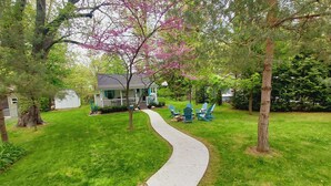 A house with a porch, a pathway, and a small garden area with chairs. - Sandy beach retreat! 500 ft to beach! 3 miles to the quaint village of Lexington (Lexington)