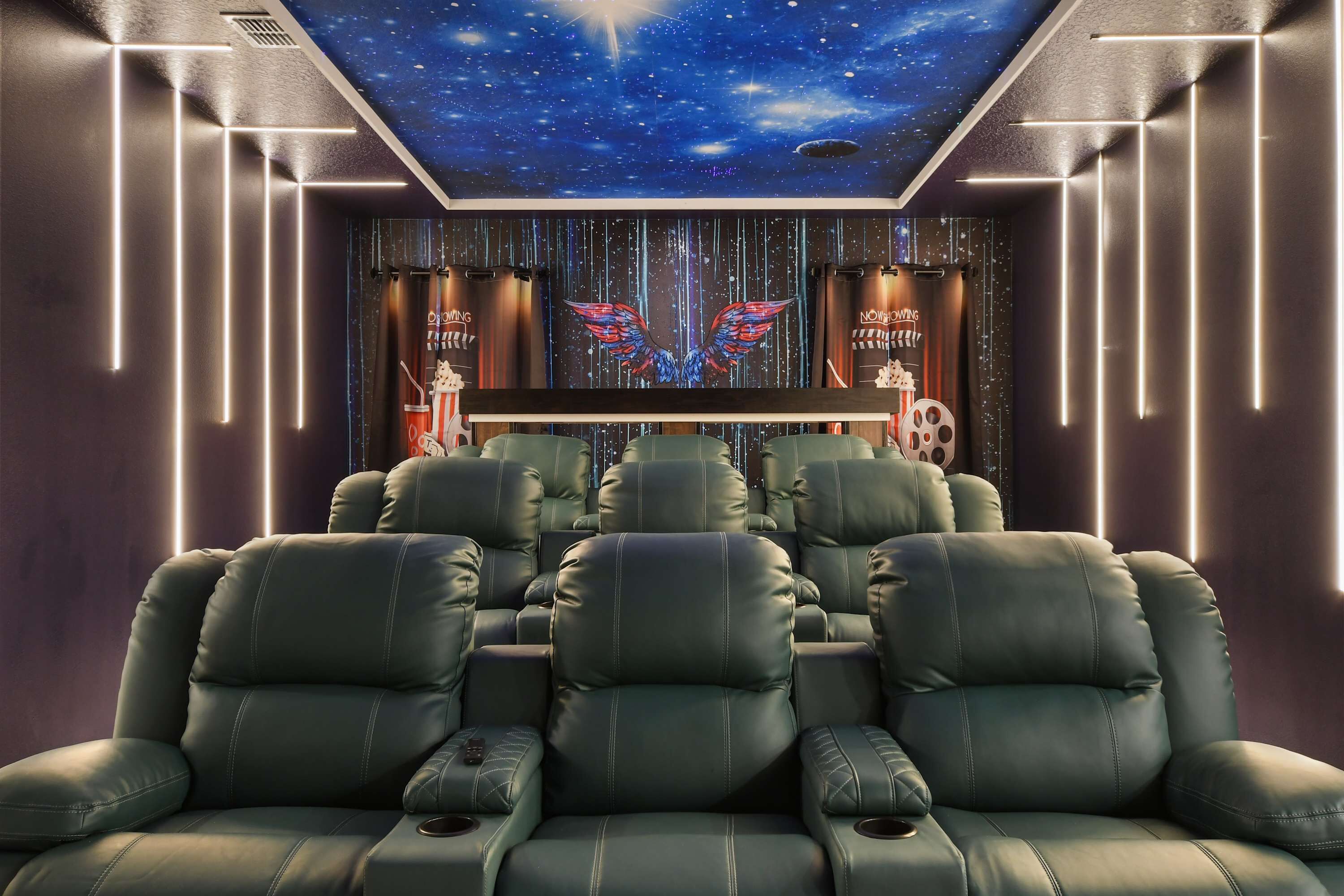 A home theater with reclining leather chairs, a starry ceiling, and a wall with a neon sign.