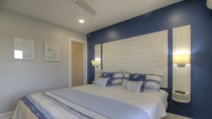 Quarto com uma cama grande, duas luminárias na parede e um ventilador de teto.