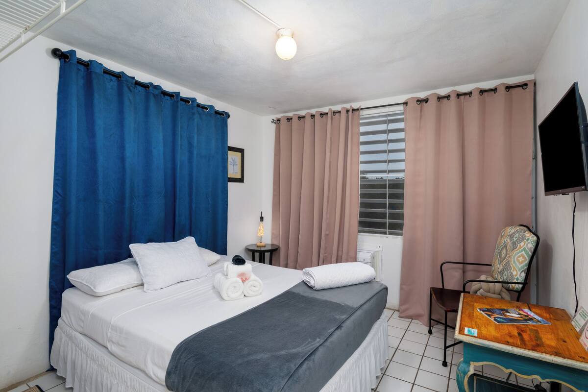Ein Hotelzimmer mit Bett, Sessel, Tisch und Fernseher.