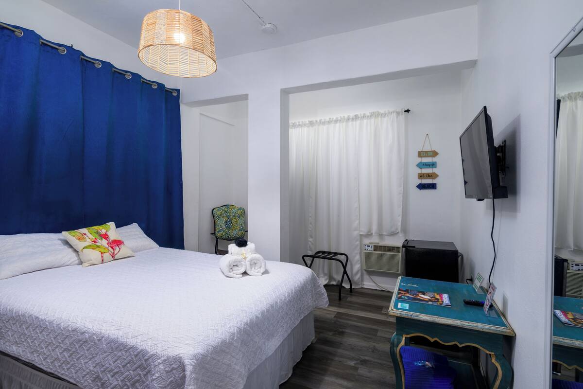 Ein ordentlich eingerichtetes Hotelzimmer mit einem großen Bett, einem Schreibtisch, einem Fernseher und einem Sessel.