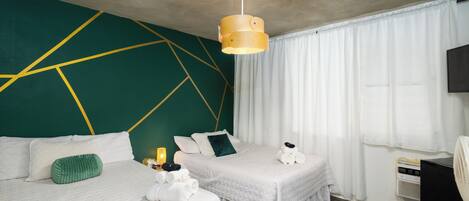 A hotel room with two beds, a green geometric wall design, a ceiling light, and a TV on the right.
