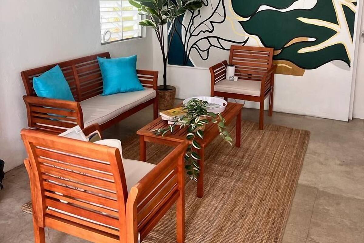 Ein Zimmer mit einer Couch, zwei Sesseln, einem Couchtisch und einem großen, abstrakten Gemälde an der Wand.