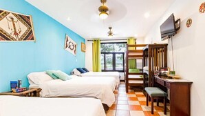A hotel room with three beds, a desk, a television, and artwork on the walls. - Posada Nena (Santa Ana)