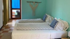 A bedroom with a bed, a ceiling fan, a wall decoration, and a view of the outside. - Posada Nena (Santa Ana)