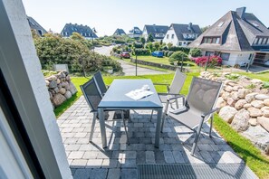Eine Terrasse mit Tisch und Stühlen, eine Steinmauer und ein Blick auf Häuser im Hintergrund.
