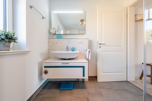 Ein modernes Badezimmer mit einem weißen Waschbecken, einem Spiegel und einer blauen Waage auf dem Boden.
