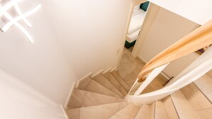 A spiral staircase with beige tiles and white walls.