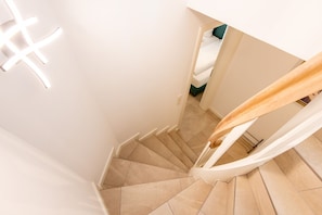 A spiral staircase with beige tiles and white walls.