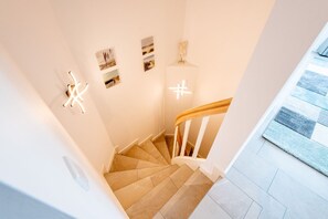 A staircase with beige tiles and white railings, leading to a landing with a light-colored rug. - Haus Dünenweg Whg. 2 - Stilvoll. Modern. Weitblick. - Objekt-id: Odh/22 (Hörnum (Sylt))